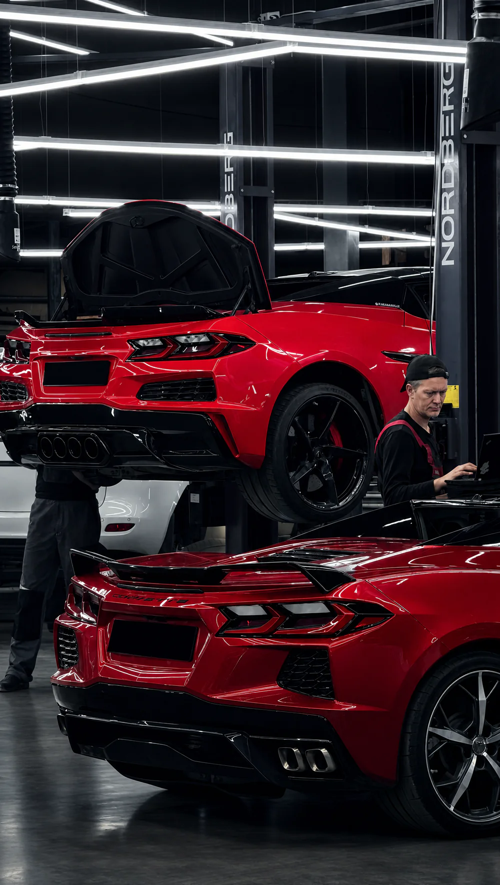 Два Chevrolet Corvette C8 в цехе Madcat Customs, мастер работает с ноутбуком